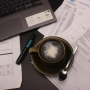 Copywriter's desk with a laptop, coffee and printed drafts