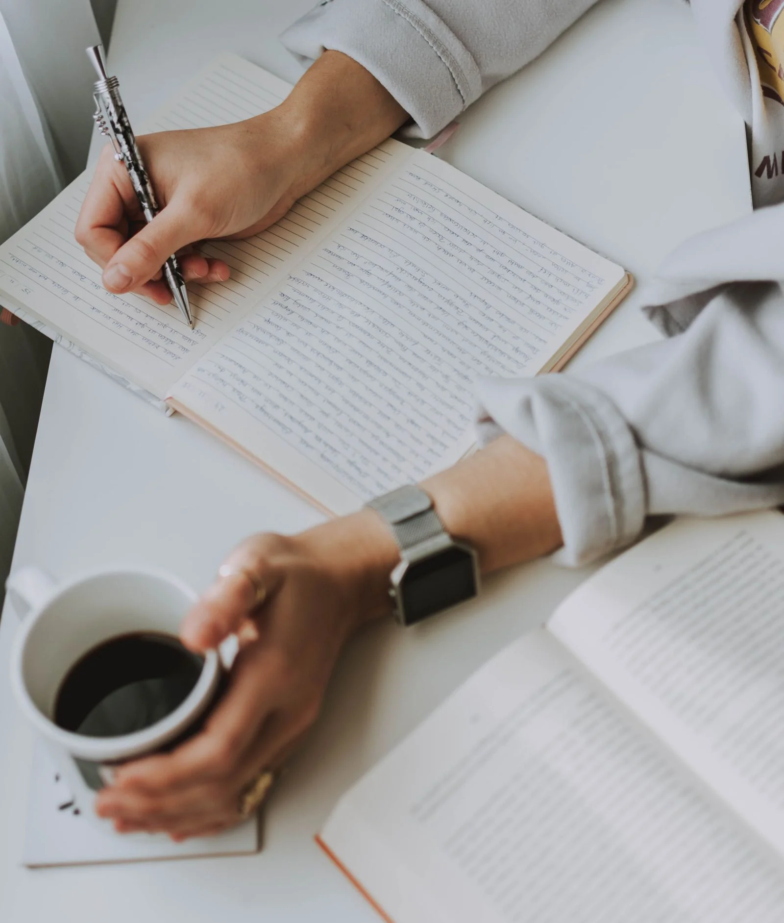 Copywriter drafting campaign lines by hand in a notebook beside a coffee