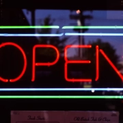 Red neon open sign glowing in a dark shop window at night