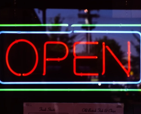 Red neon open sign glowing in a dark shop window at night