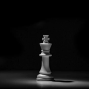 A single white chess king lit by one light source on a dark board