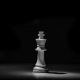 A single white chess king lit by one light source on a dark board