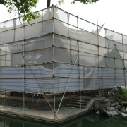 A building facade completely wrapped in scaffolding and protective netting during renovation