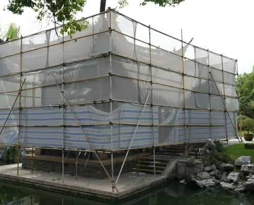 A building facade completely wrapped in scaffolding and protective netting during renovation