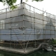 A building facade completely wrapped in scaffolding and protective netting during renovation