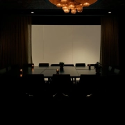 An empty, dimly lit conference room lit by a chandelier, waiting for a pitch meeting to begin
