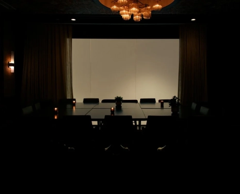 An empty, dimly lit conference room lit by a chandelier, waiting for a pitch meeting to begin