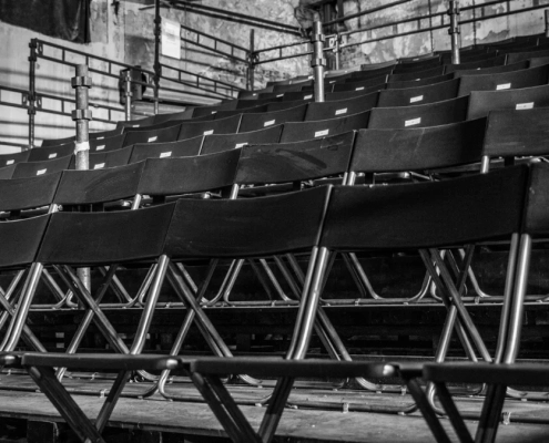 Rows of empty black chairs in tiered seating, shot in black and white